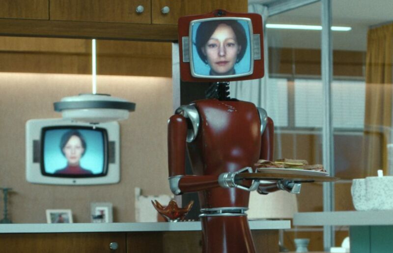 Fotograma de la serie Cassandra (Netflix): un robot doméstico con la cara de Cassandra proyectada en una pantalla lleva una bandeja con comida.